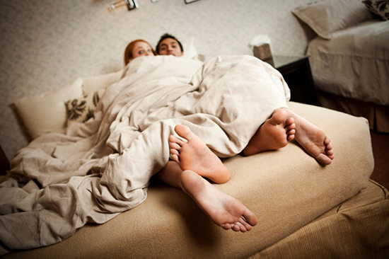 Couple caught in bed with feet hanging out the covers